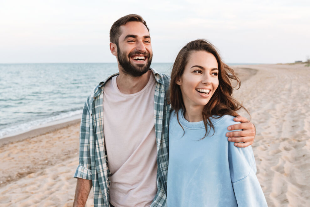 Beautiful young smiling couple spending time at the beach, walking, embracing